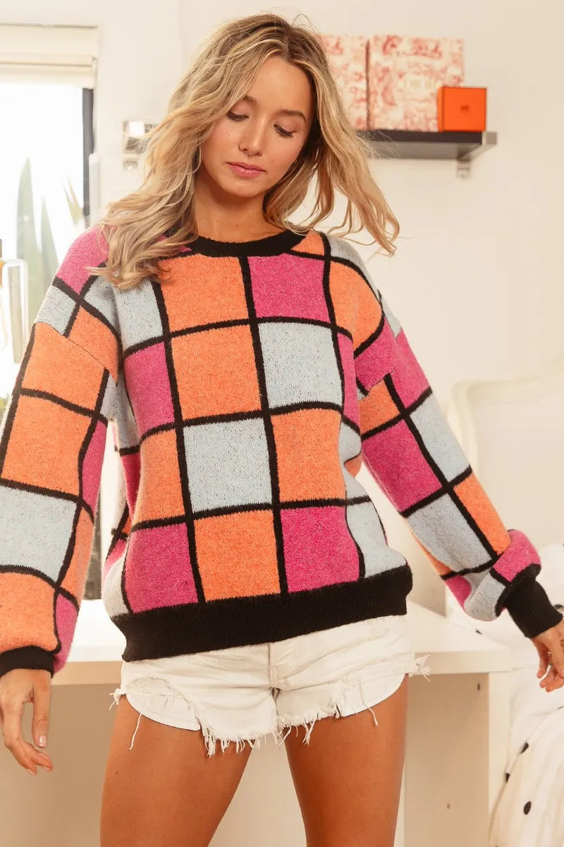 Colorful oversized sweater with pink, orange, and blue checker pattern outlined in black.