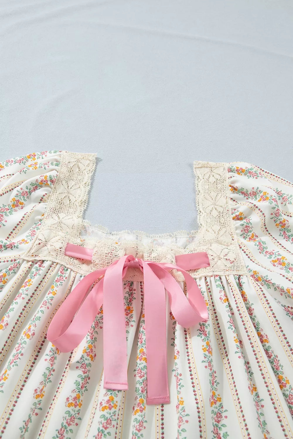 cream floral stripe babydoll dress with lace neckline, flutter sleeves, and pink satin bow detail