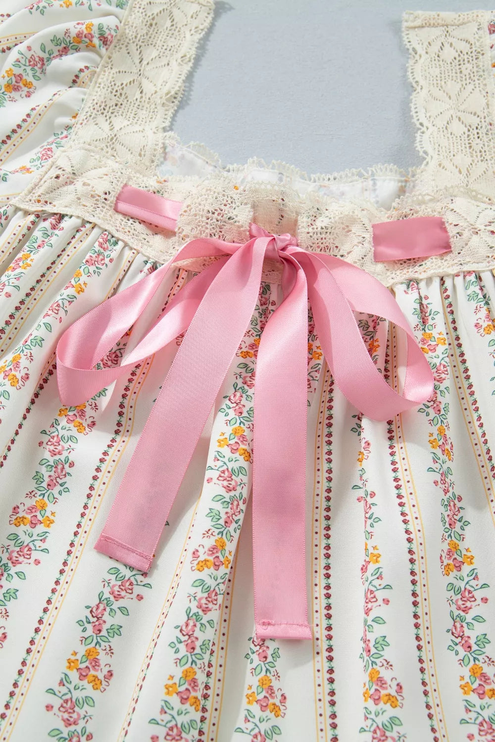 cream floral stripe babydoll dress with lace neckline, flutter sleeves, and pink satin bow detail
