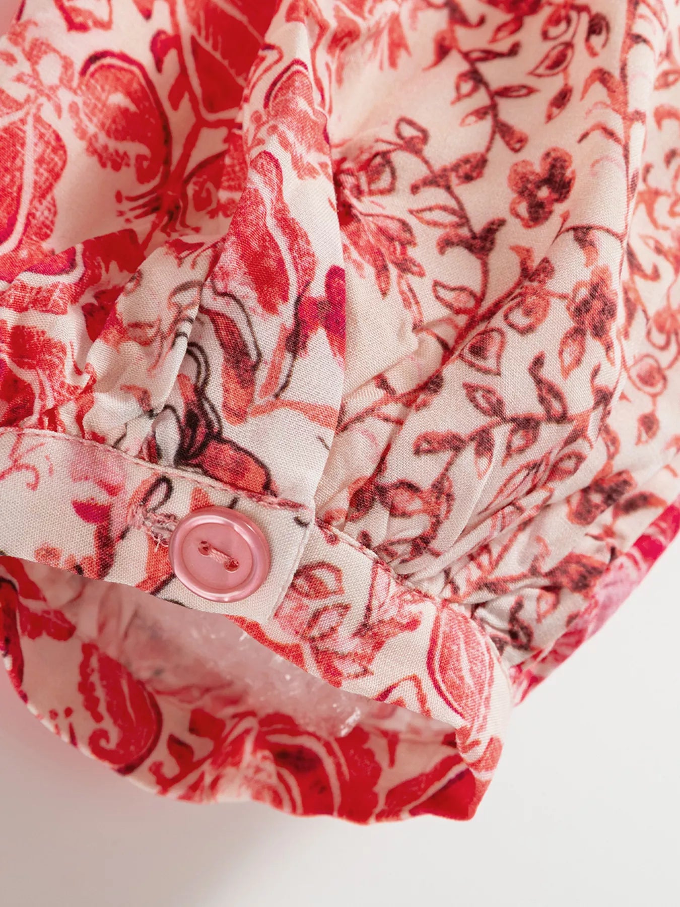 Rosé Reverie Mini Dress – flowy floral print boho dress with tassel tie neckline and ruffle details.