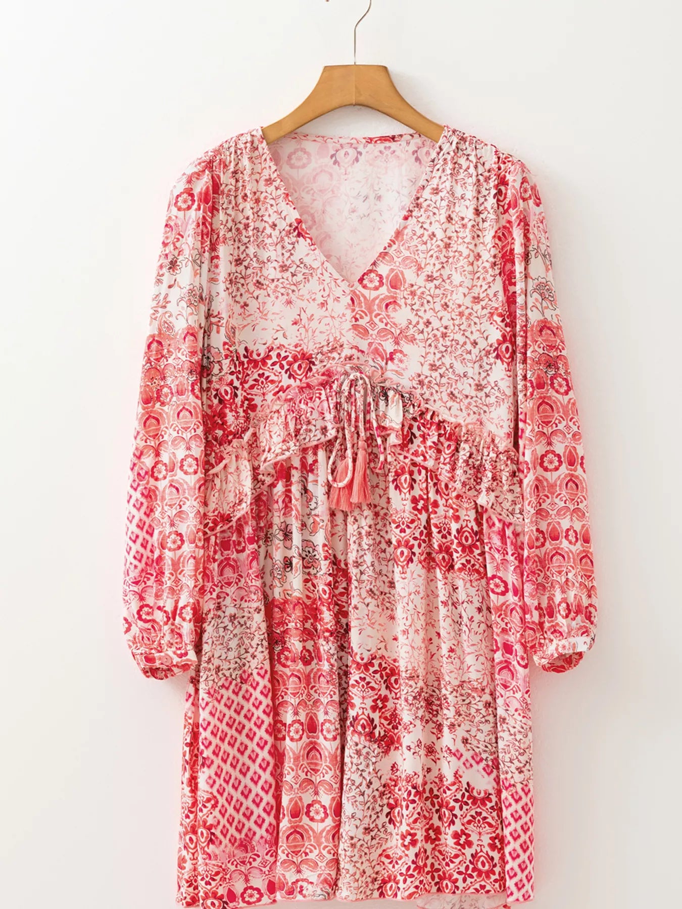 Rosé Reverie Mini Dress – flowy floral print boho dress with tassel tie neckline and ruffle details.
