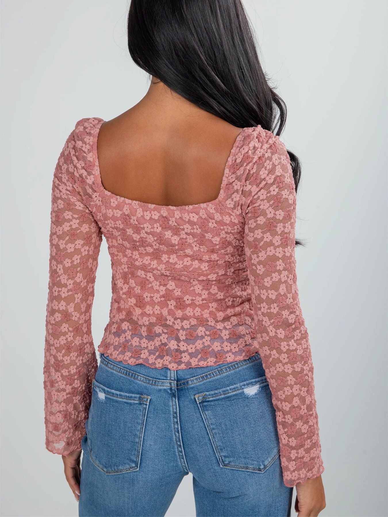 Woman wearing a dusty rose long sleeve lace top with front tie detail