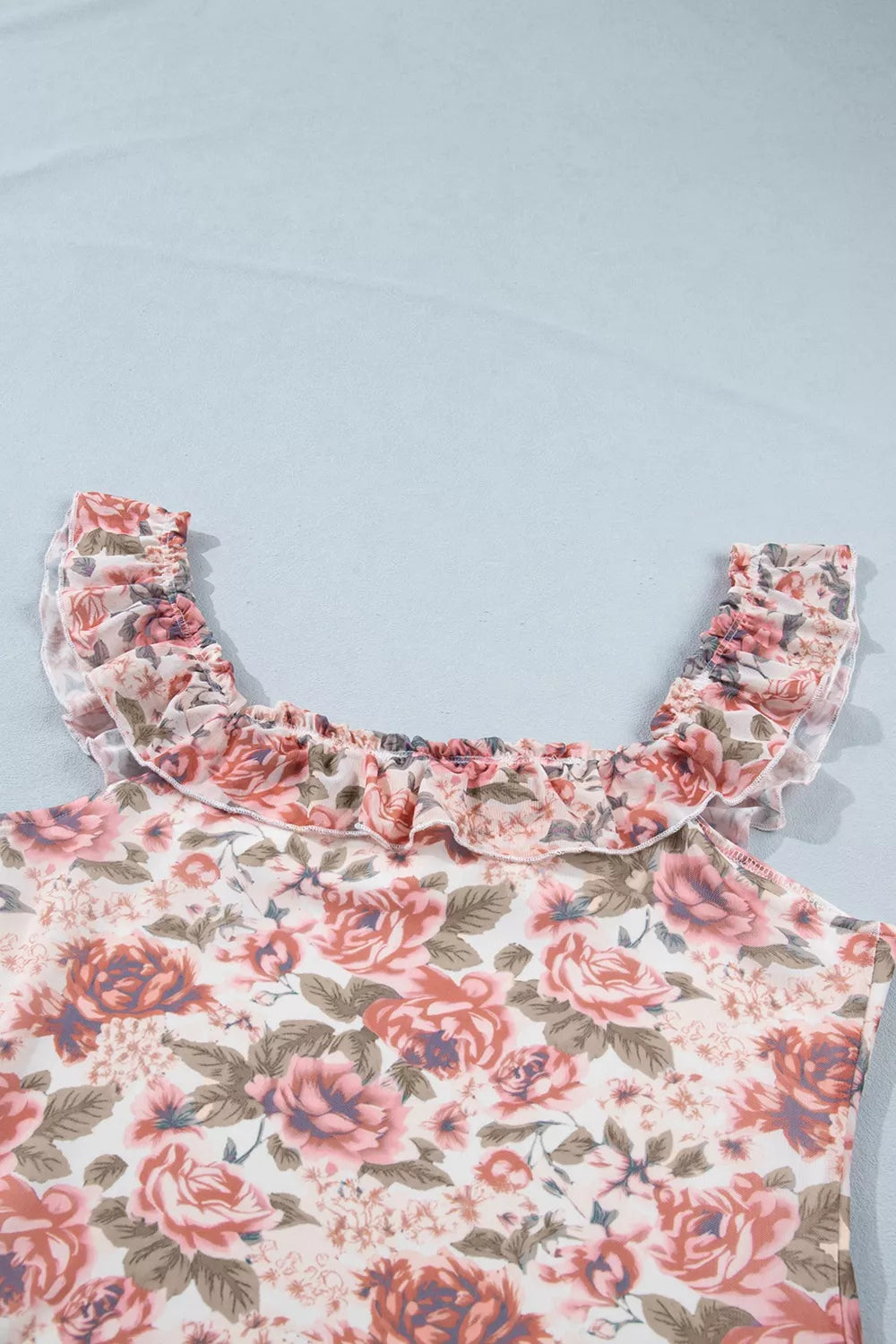 Floral ruffle sleeve top with a romantic rose print, square neckline, and slightly stretchy fit styled with jeans.