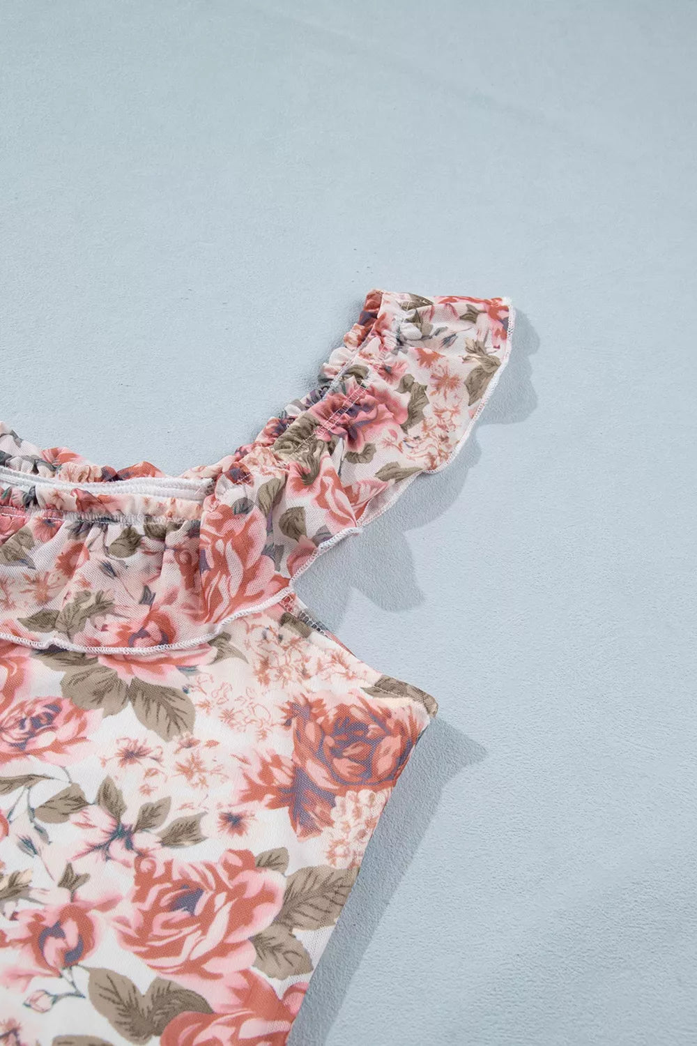 Floral ruffle sleeve top with a romantic rose print, square neckline, and slightly stretchy fit styled with jeans.