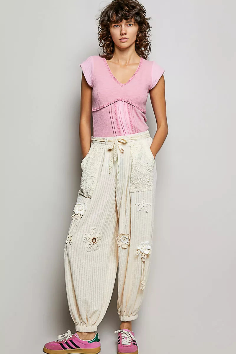 Woman wearing a pink textured V-neck cotton top with crochet trim and empire seam detail