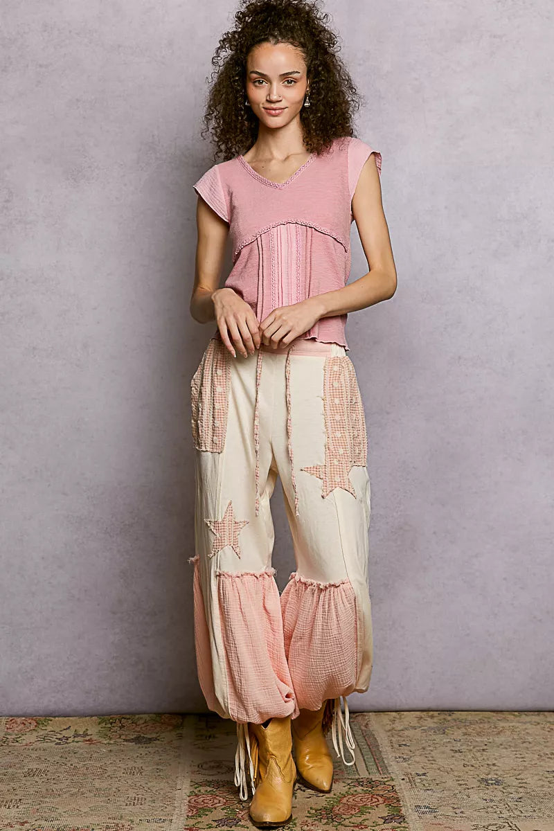 Woman wearing a pink textured V-neck cotton top with crochet trim and empire seam detail