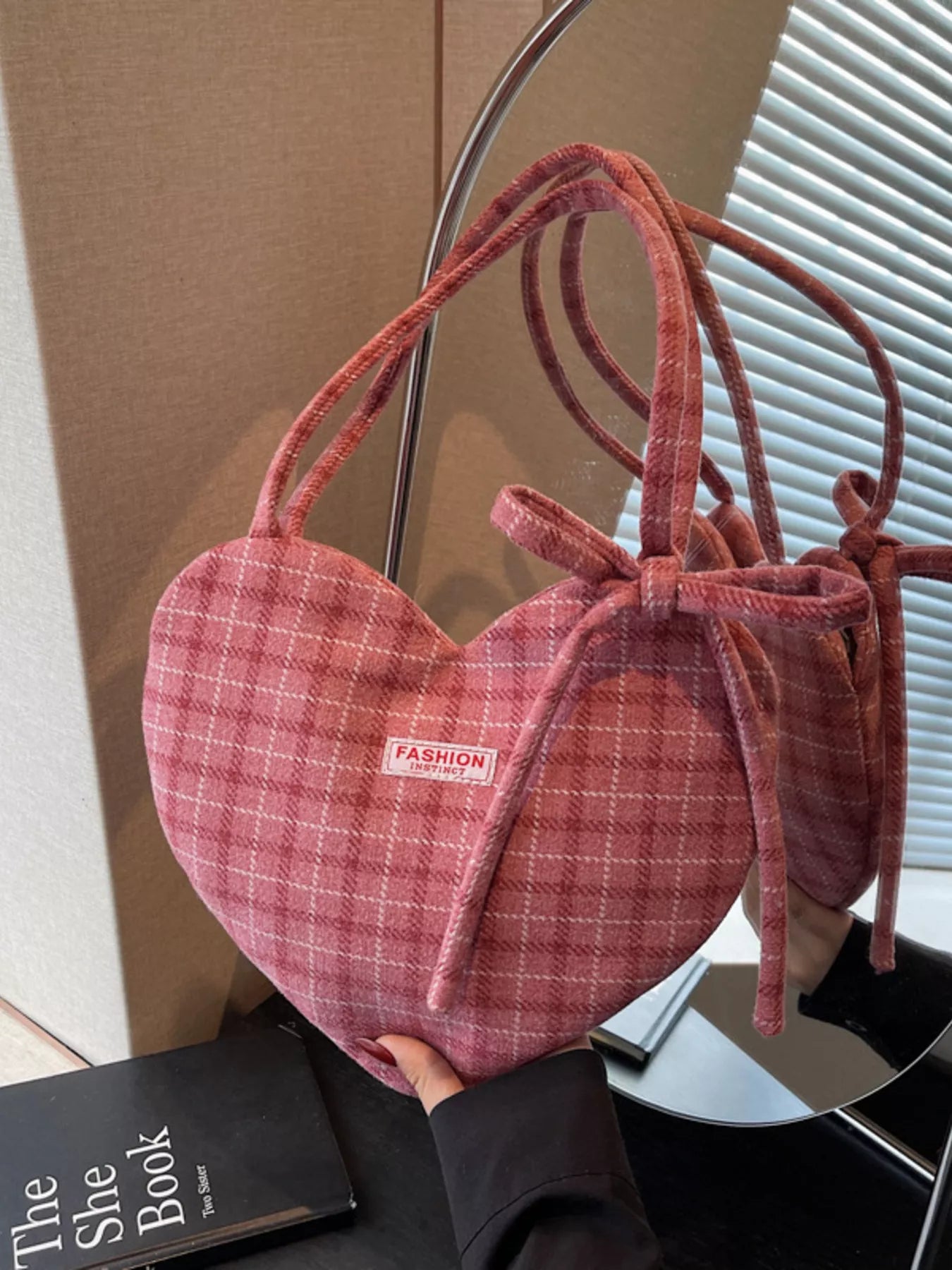 Pink heart-shaped tote bag with bow detail, styled over a black blazer for a romantic whimsical look