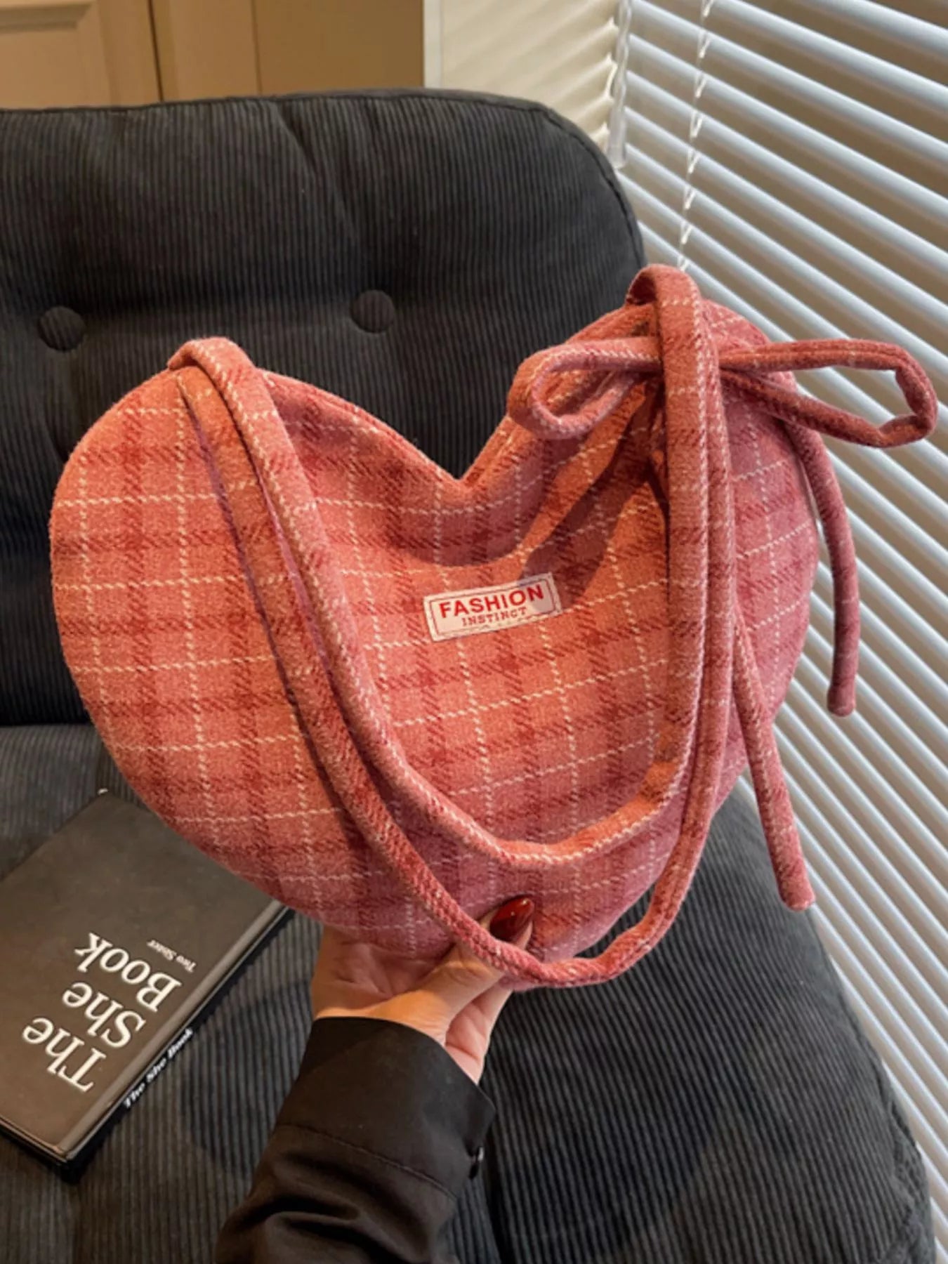 Pink heart-shaped tote bag with bow detail, styled over a black blazer for a romantic whimsical look