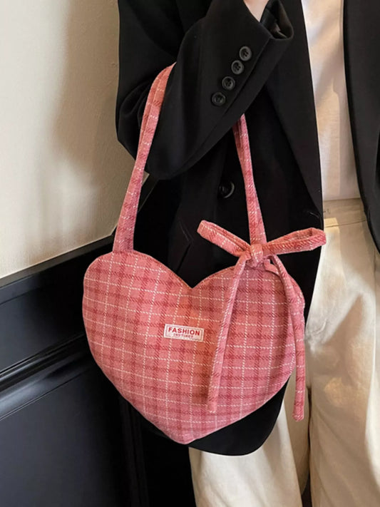 Pink heart-shaped tote bag with bow detail, styled over a black blazer for a romantic whimsical look