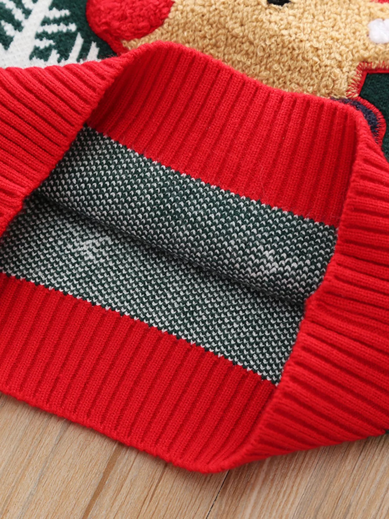 Kids’ green reindeer Christmas sweater with green trim and white snowflakes.