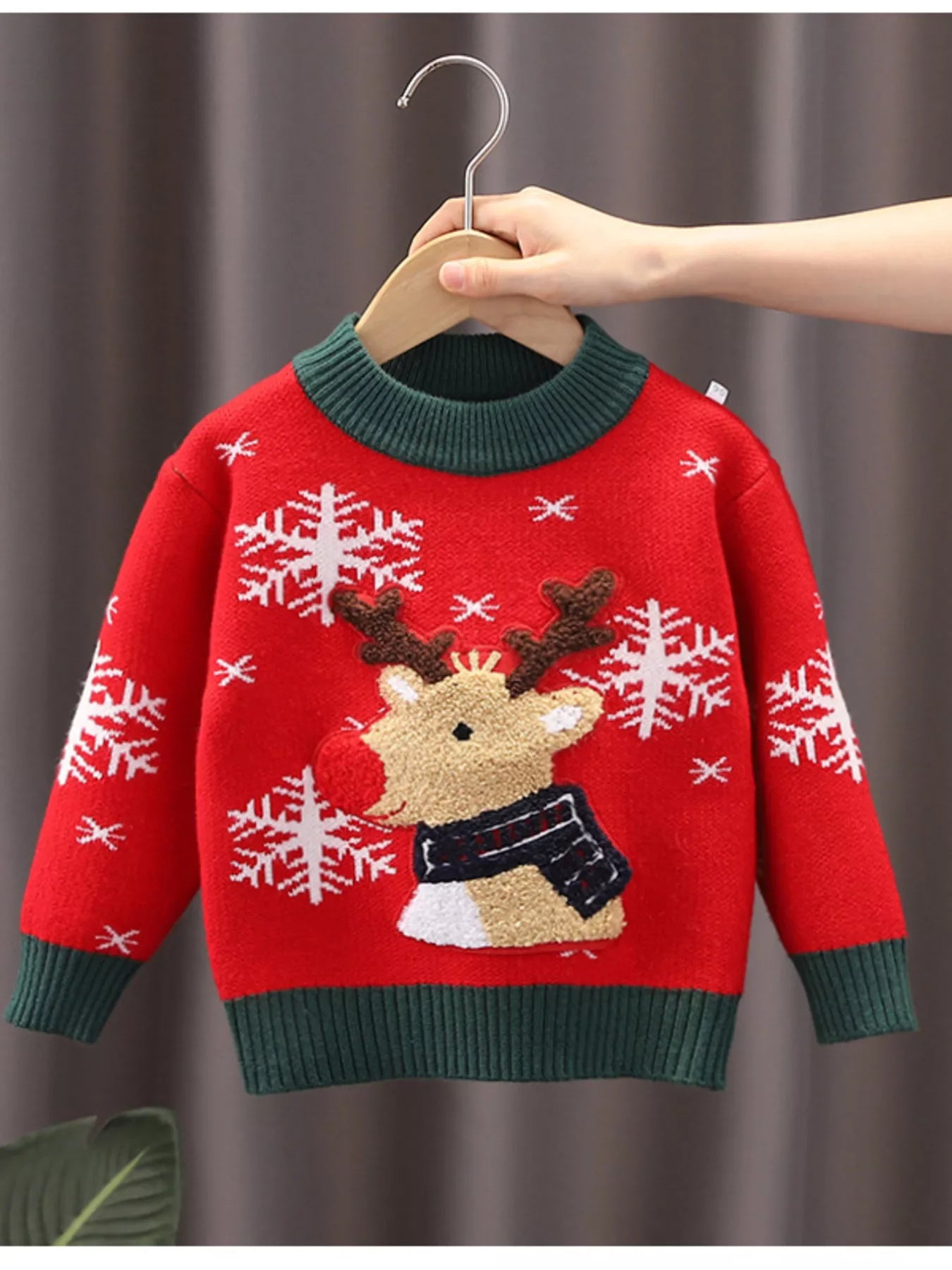 Kids’ red reindeer Christmas sweater with green trim and white snowflakes.