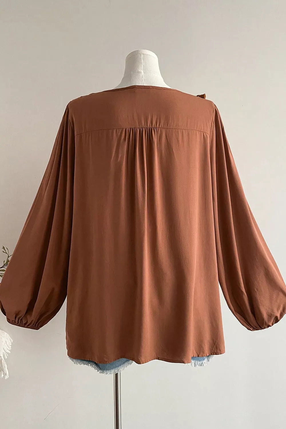 Rustic boho blouse with embroidered front detail, tassel trim, tied neckline, flowy long sleeves, and slightly stretchy fabric.