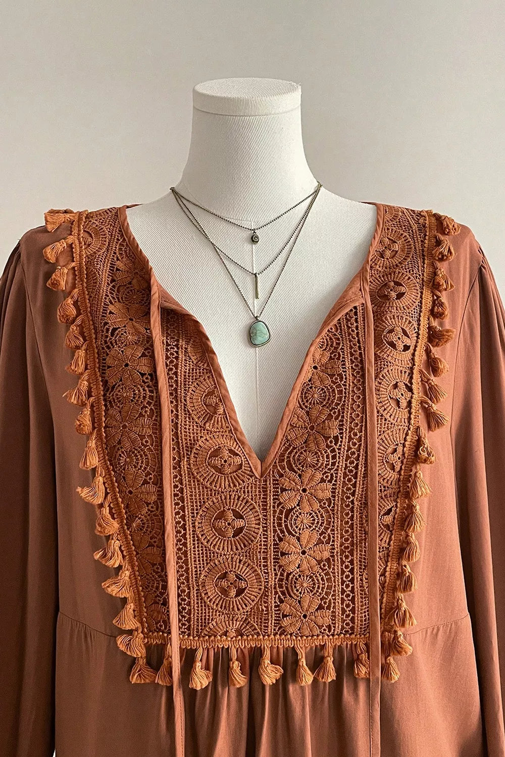 Rustic boho blouse with embroidered front detail, tassel trim, tied neckline, flowy long sleeves, and slightly stretchy fabric.