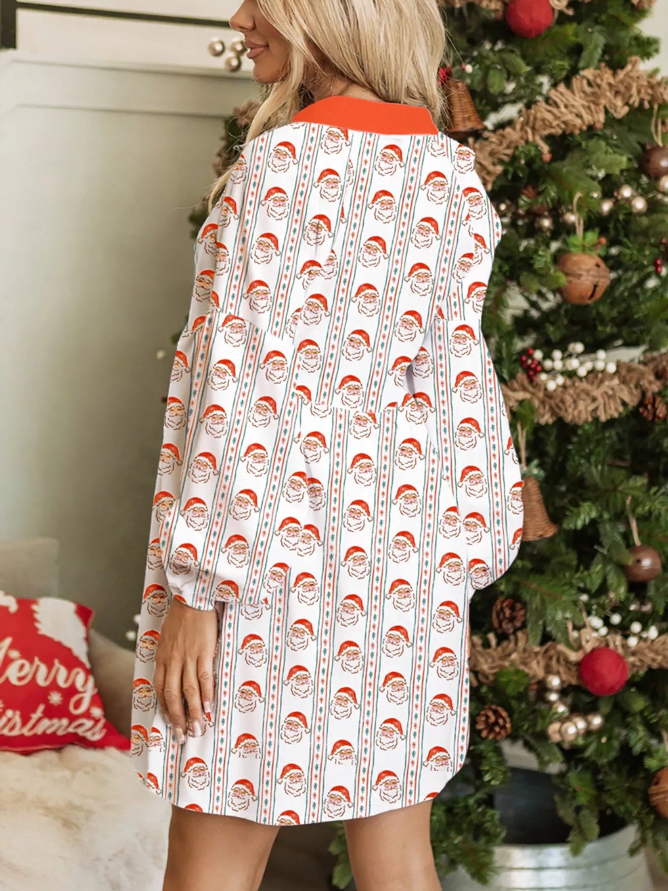 White swing dress with vertical Santa print stripes and red button placket, worn beside a decorated Christmas tree.