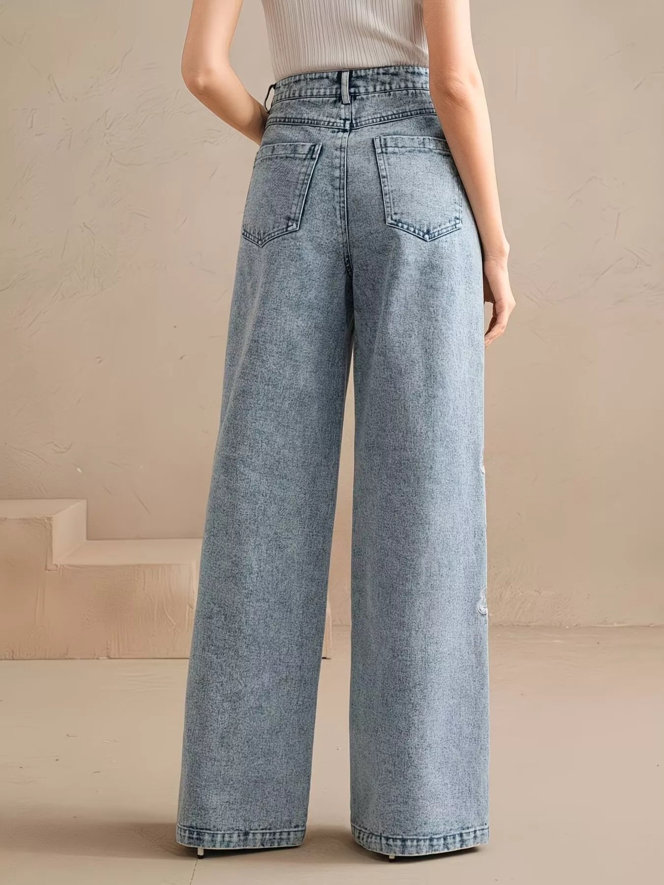Wide-leg jeans with floral embroidery down one leg, seam detailing, structured cotton-blend denim, and a relaxed statement fit.