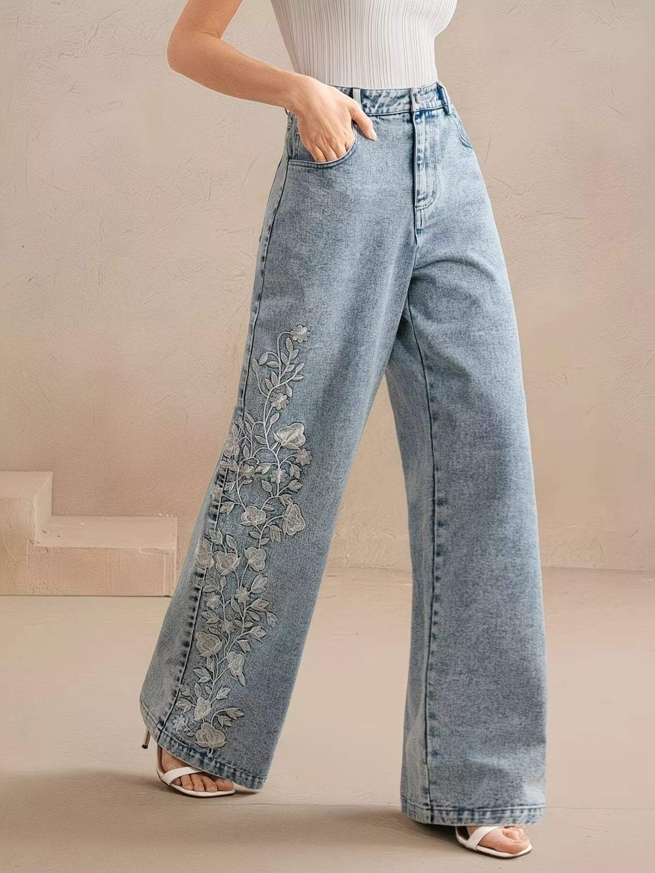 Wide-leg jeans with floral embroidery down one leg, seam detailing, structured cotton-blend denim, and a relaxed statement fit.
