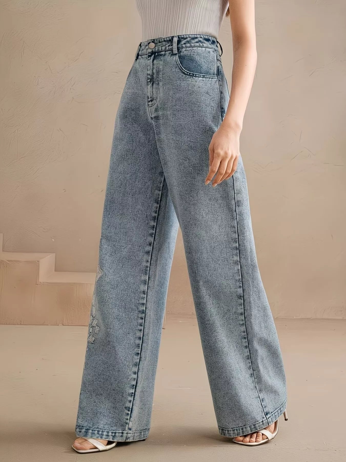Wide-leg jeans with floral embroidery down one leg, seam detailing, structured cotton-blend denim, and a relaxed statement fit.