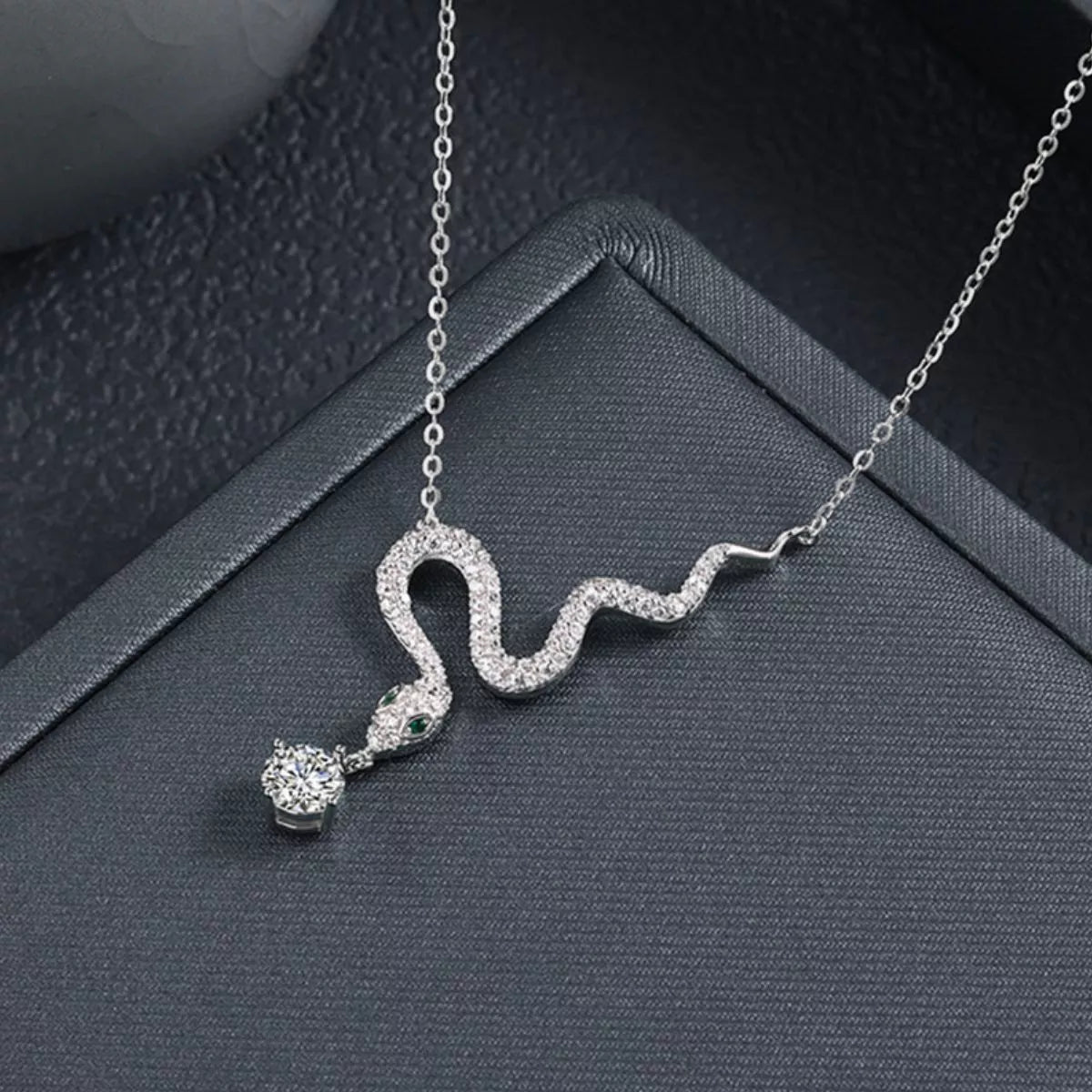 Sterling silver snake pendant necklace with a moissanite drop and green accent eyes.
