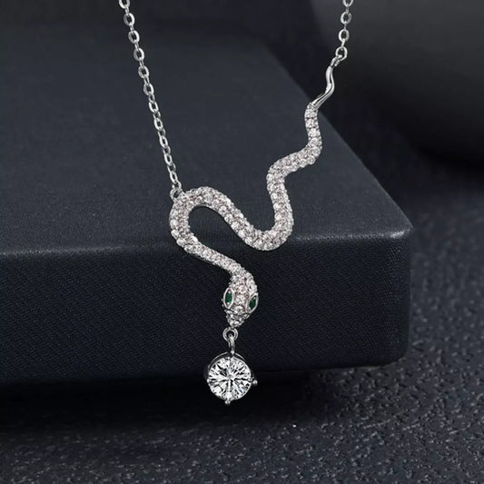 Sterling silver snake pendant necklace with a moissanite drop and green accent eyes.