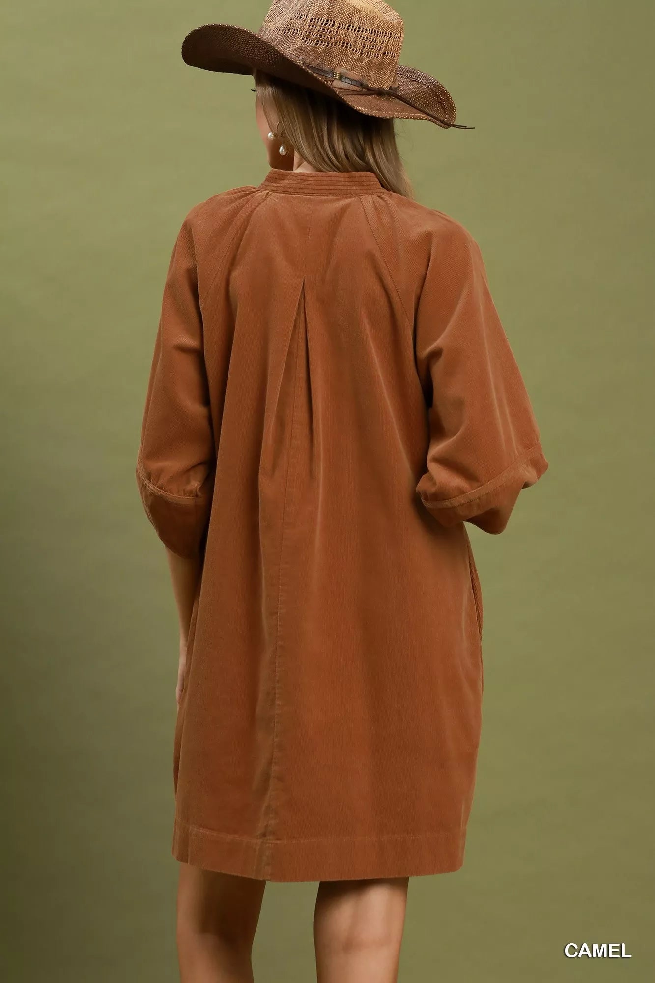 Camel corduroy shift dress with V-neckline, puff sleeves, side pockets, and relaxed fit styled with a wide-brim hat.