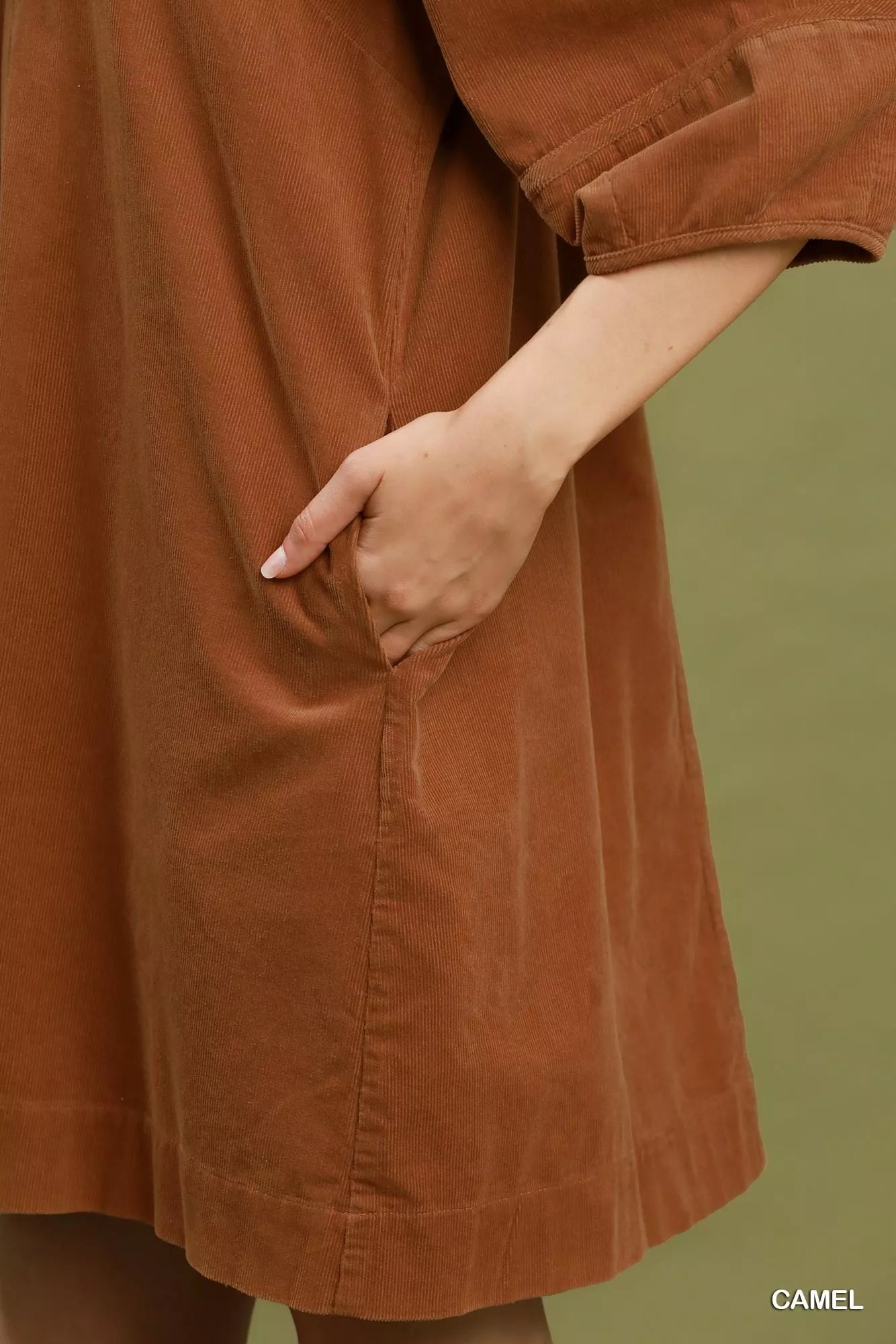 Camel corduroy shift dress with V-neckline, puff sleeves, side pockets, and relaxed fit styled with a wide-brim hat.