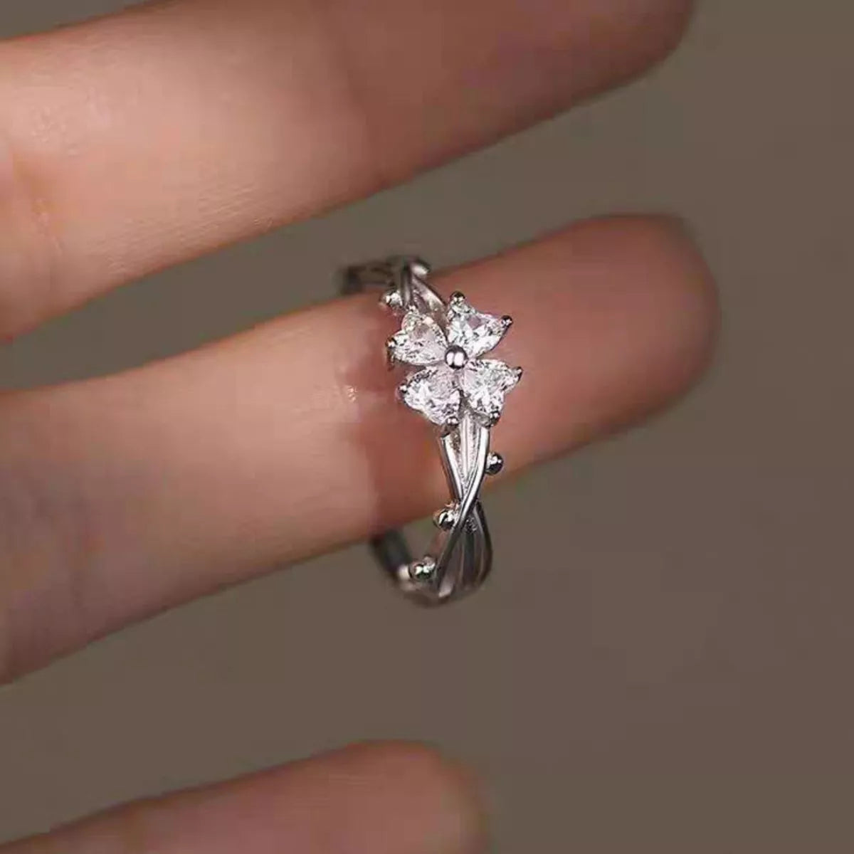 Adjustable 925 sterling silver floral branch ring with sparkling zircon flower accents worn on a finger.