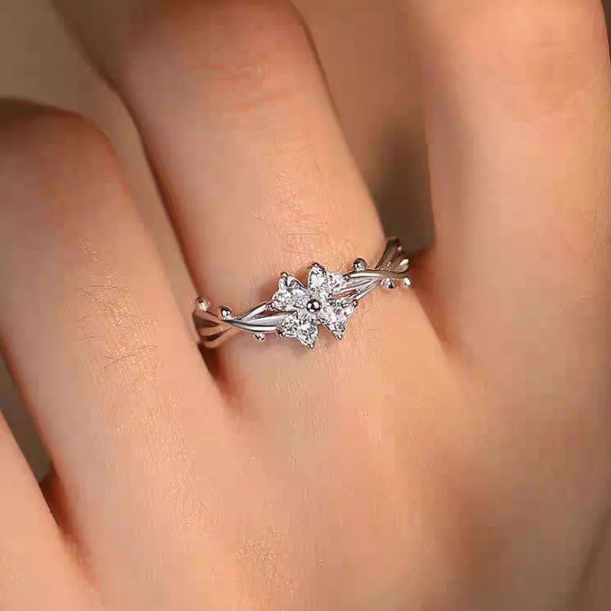 Adjustable 925 sterling silver floral branch ring with sparkling zircon flower accents worn on a finger.