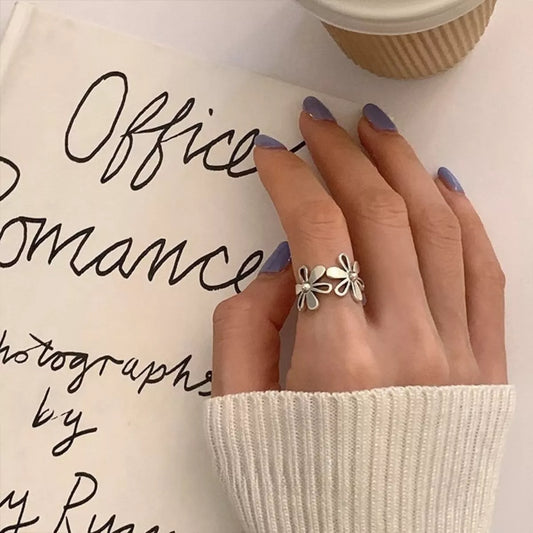 Delicate sterling silver floral ring with open petal design worn on hand