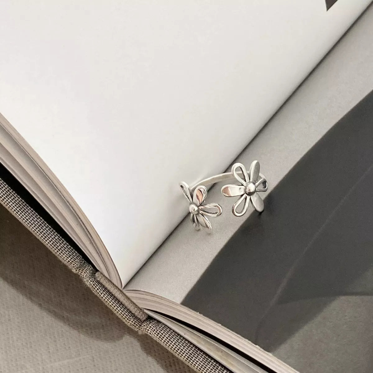 Delicate sterling silver floral ring with open petal design worn on hand