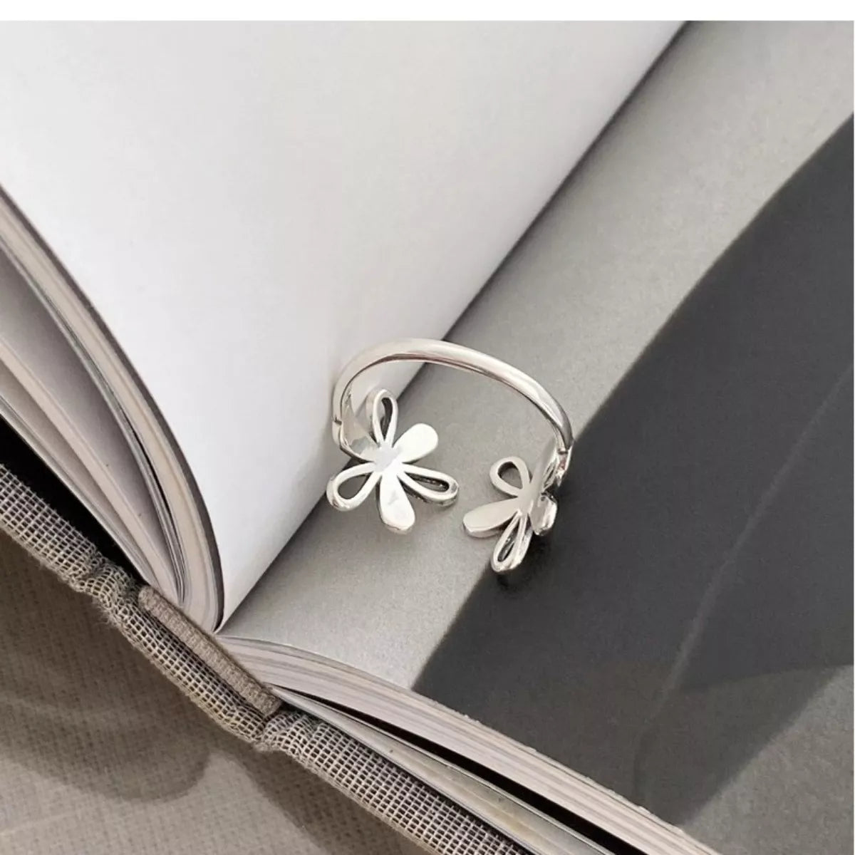 Delicate sterling silver floral ring with open petal design worn on hand
