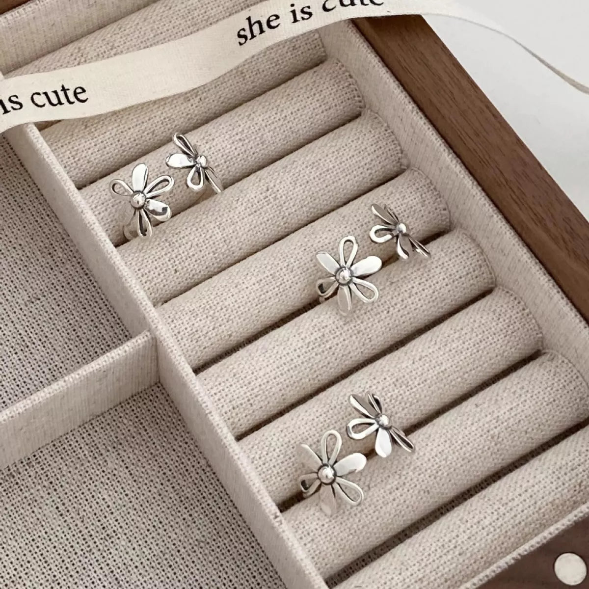 Delicate sterling silver floral ring with open petal design worn on hand