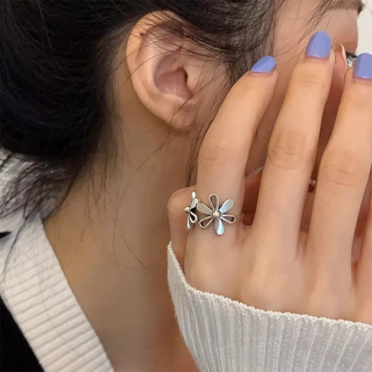Delicate sterling silver floral ring with open petal design worn on hand