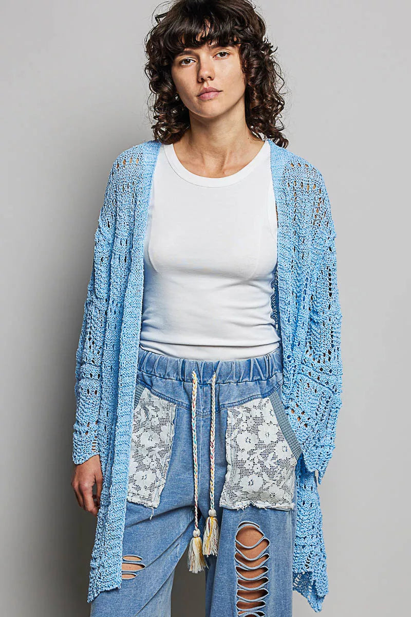Woman wearing a lightweight openwork blue cardigan over a white tank and jeans