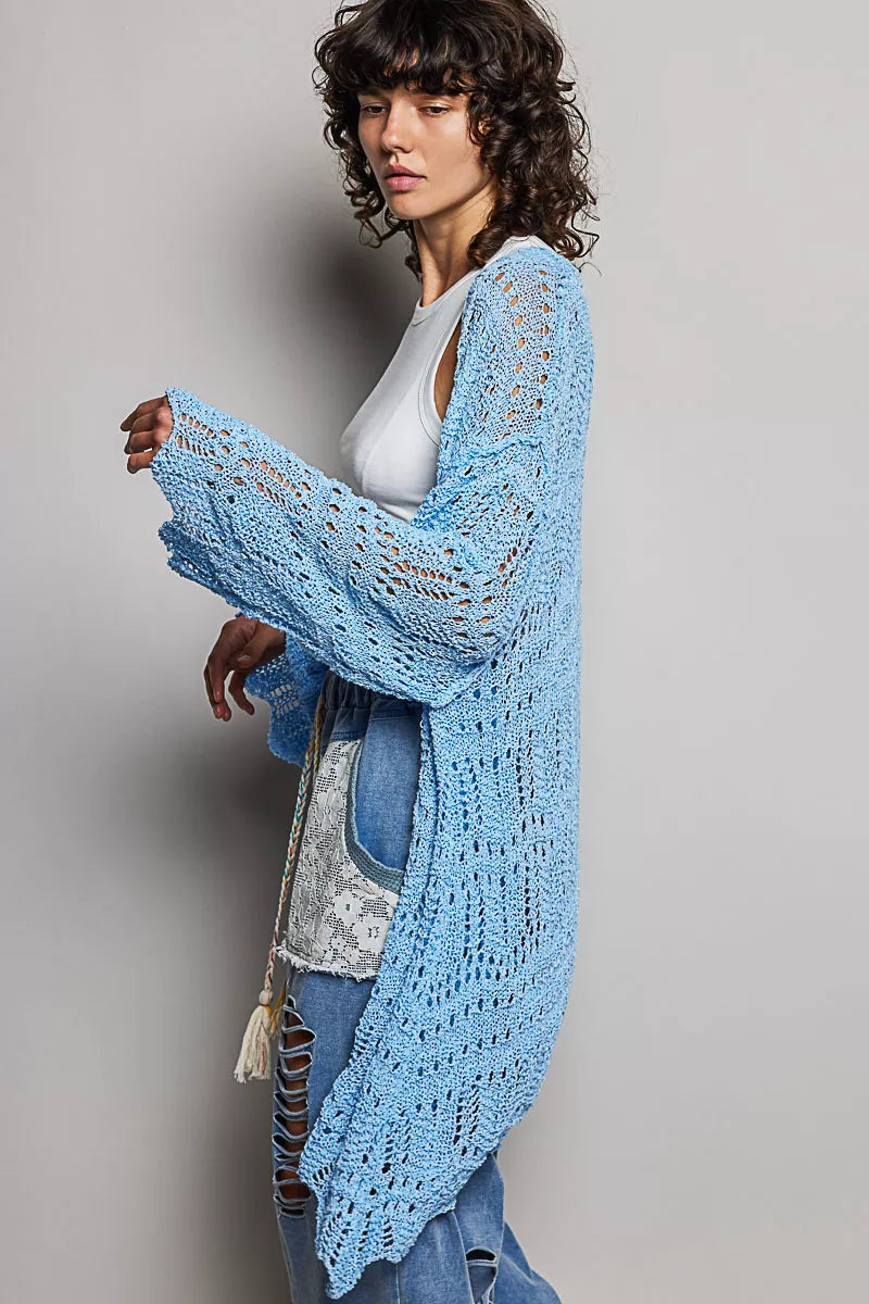 Woman wearing a lightweight openwork blue cardigan over a white tank and jeans