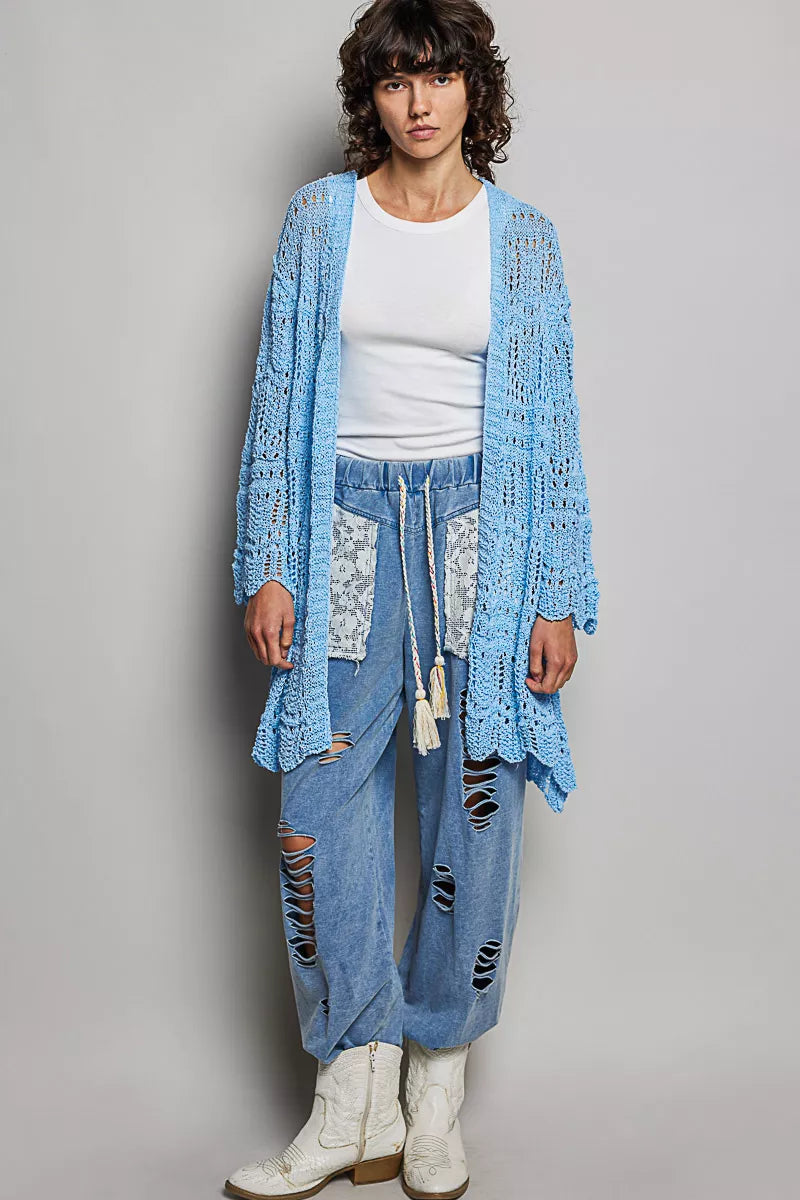 Woman wearing a lightweight openwork blue cardigan over a white tank and jeans