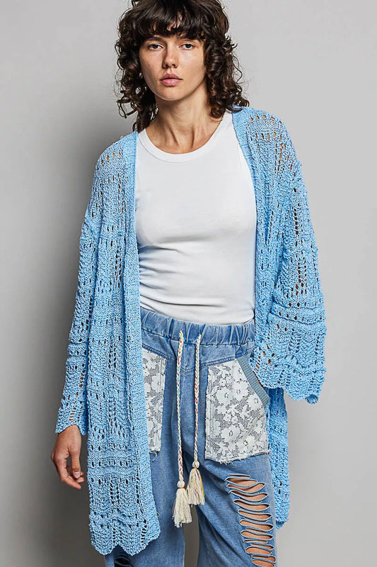 Woman wearing a lightweight openwork blue cardigan over a white tank and jeans