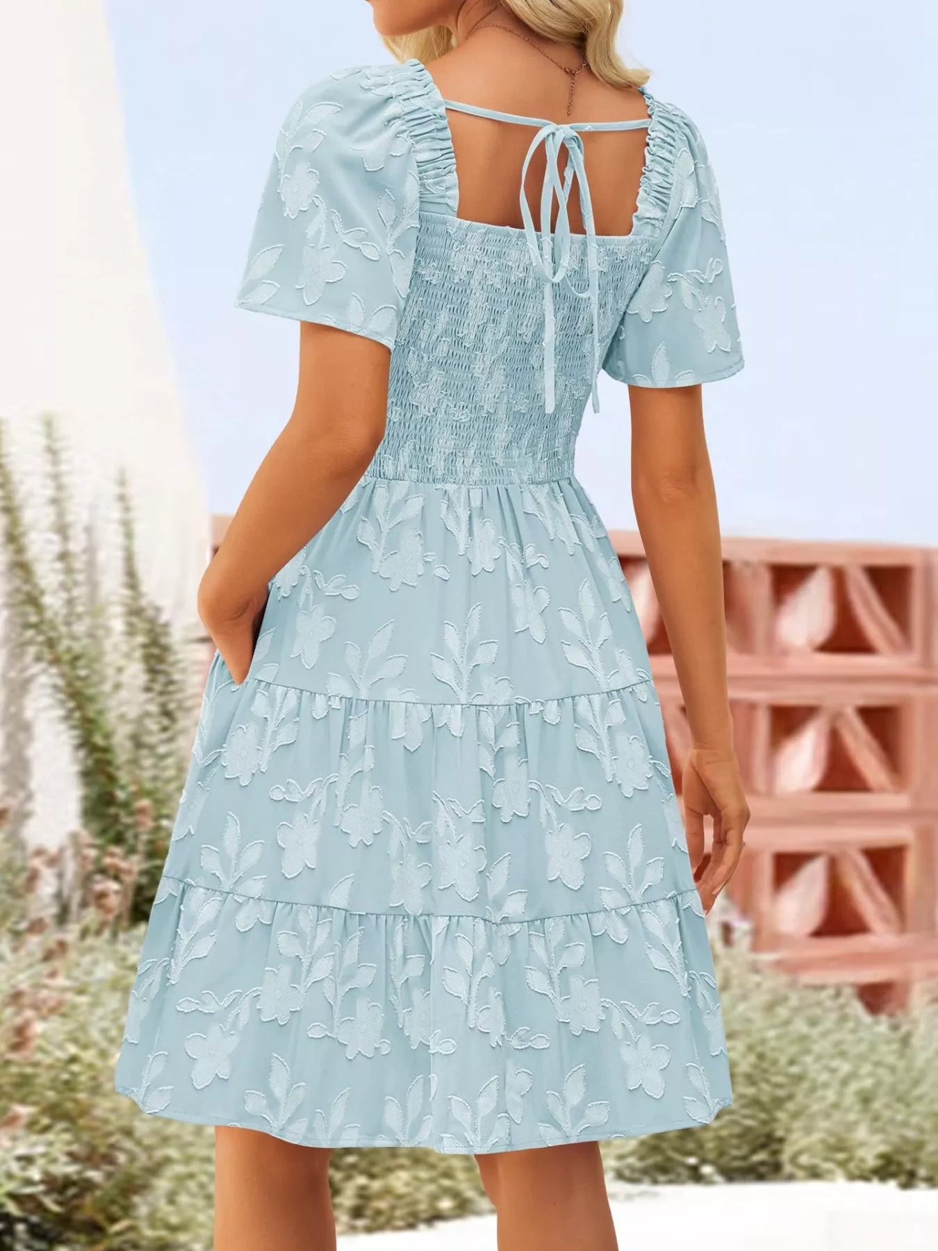 Tiered dress with smocked bodice, flutter sleeves, and textured floral fabric