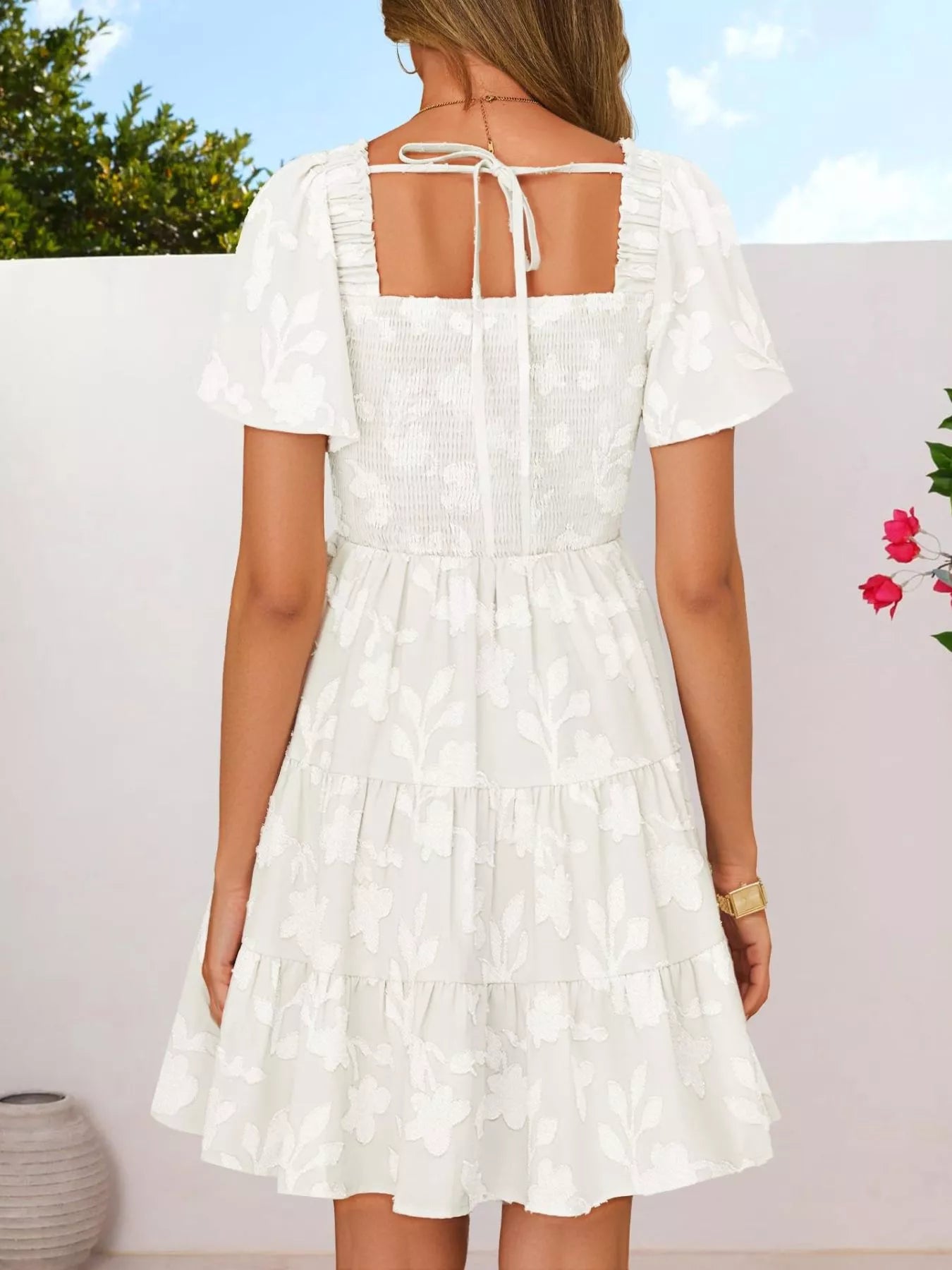 Tiered dress with smocked bodice, flutter sleeves, and textured floral fabric