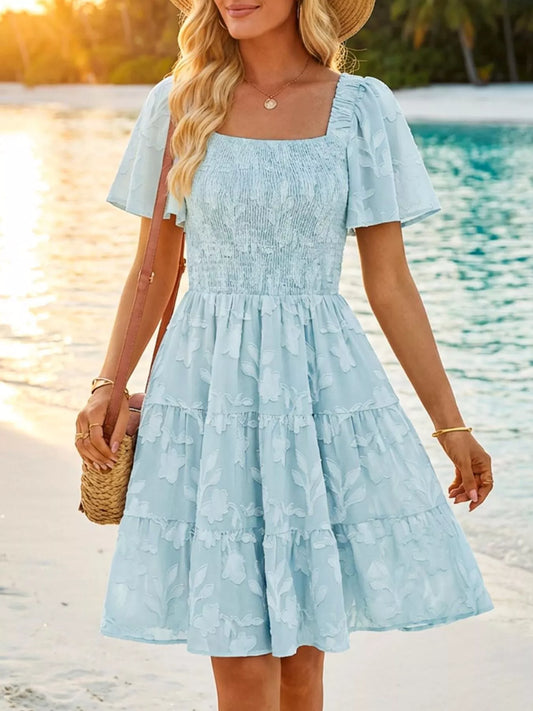 Tiered dress with smocked bodice, flutter sleeves, and textured floral fabric