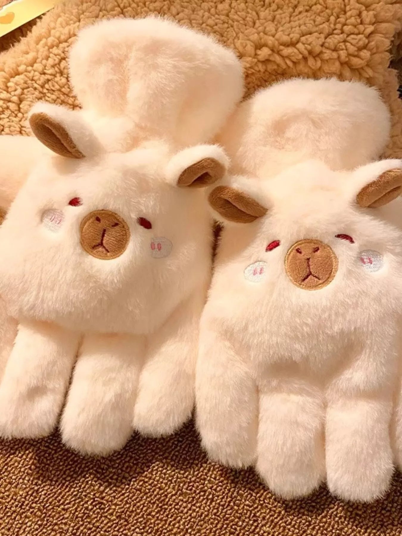 Pair of fluffy lamb-shaped plush gloves in soft neutral tones, cozy and cute winter handwear