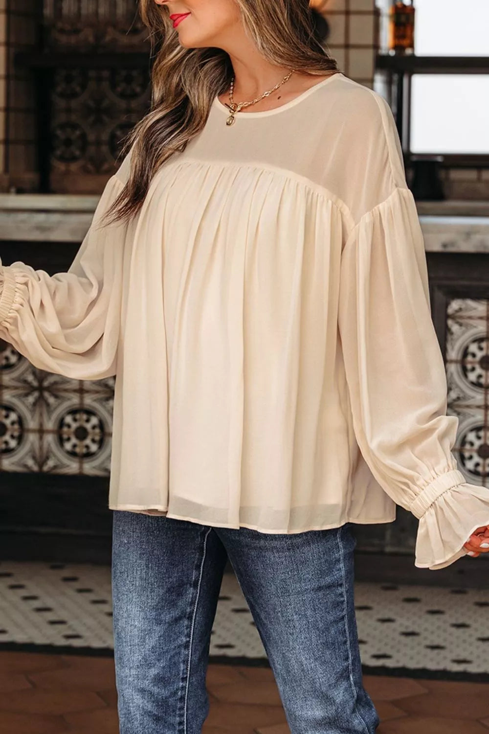 Flowy ruffle sleeve blouse with a relaxed silhouette styled with jeans and a casual coffee cup.
