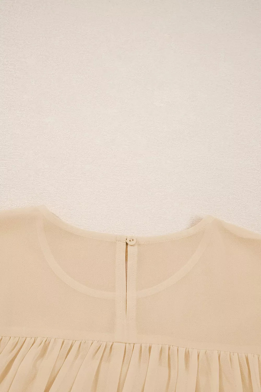 Flowy ruffle sleeve blouse with a relaxed silhouette styled with jeans and a casual coffee cup.