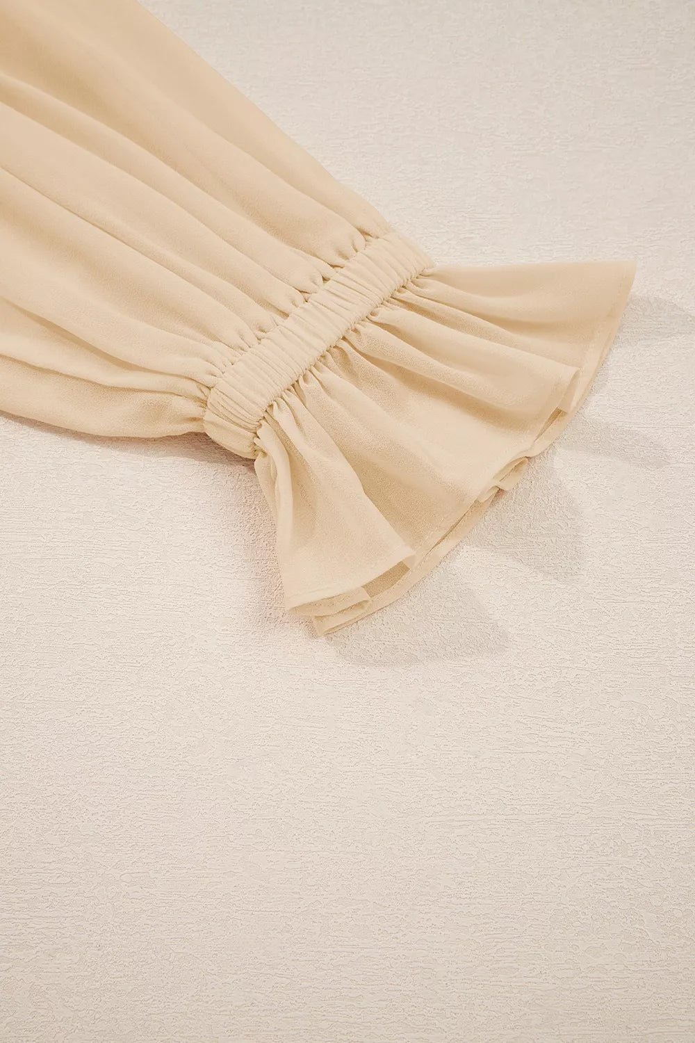 Flowy ruffle sleeve blouse with a relaxed silhouette styled with jeans and a casual coffee cup.