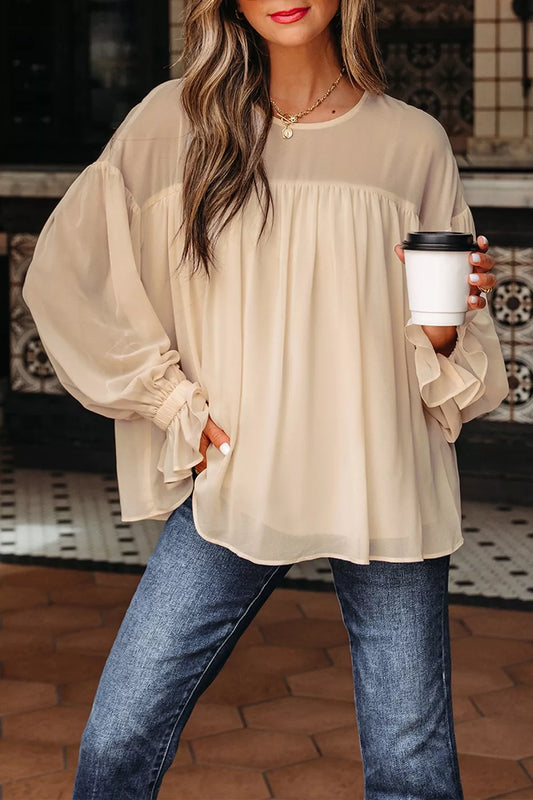 Flowy ruffle sleeve blouse with a relaxed silhouette styled with jeans and a casual coffee cup.