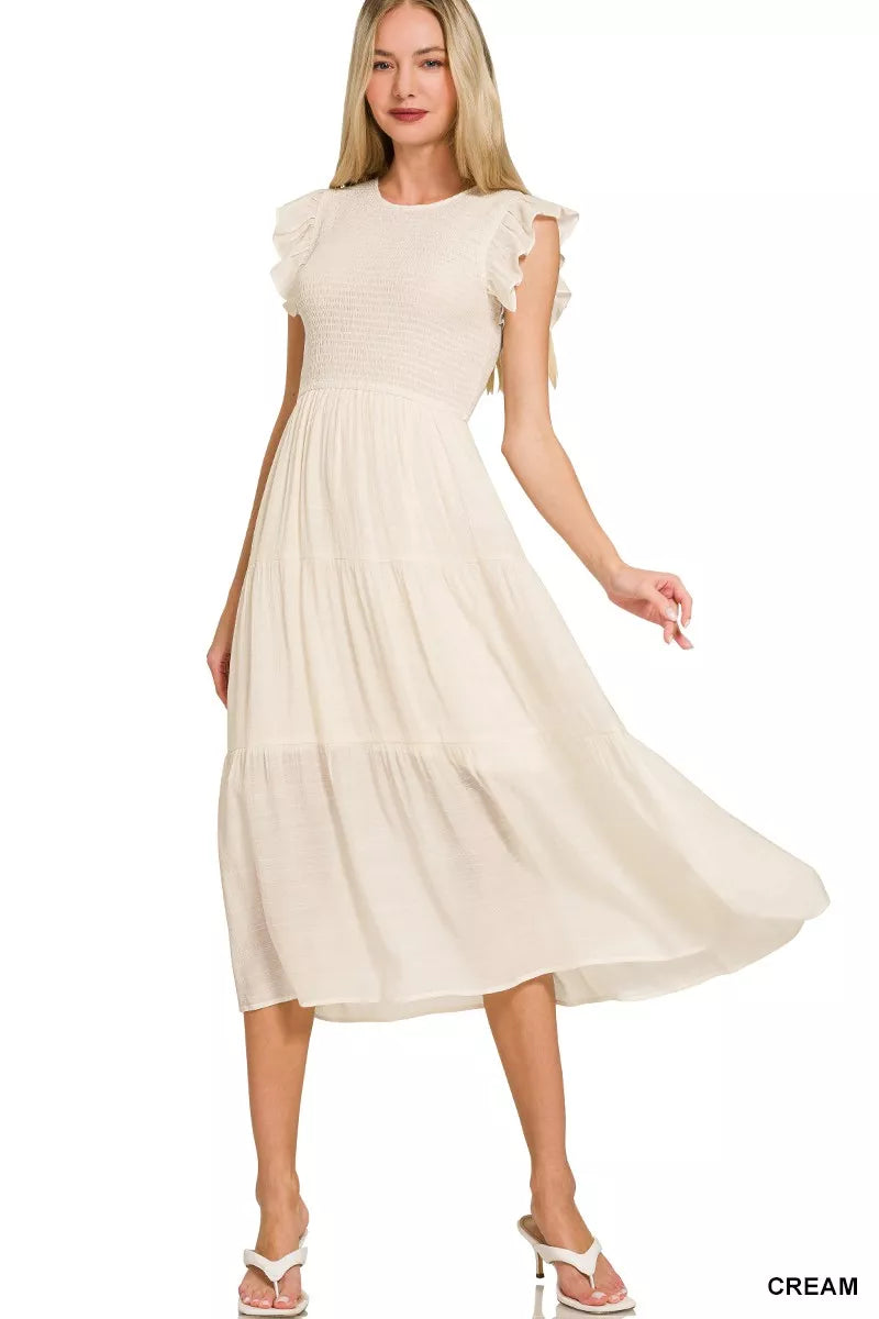 Cream smocked midi dress with ruffle sleeves and tiered skirt on model