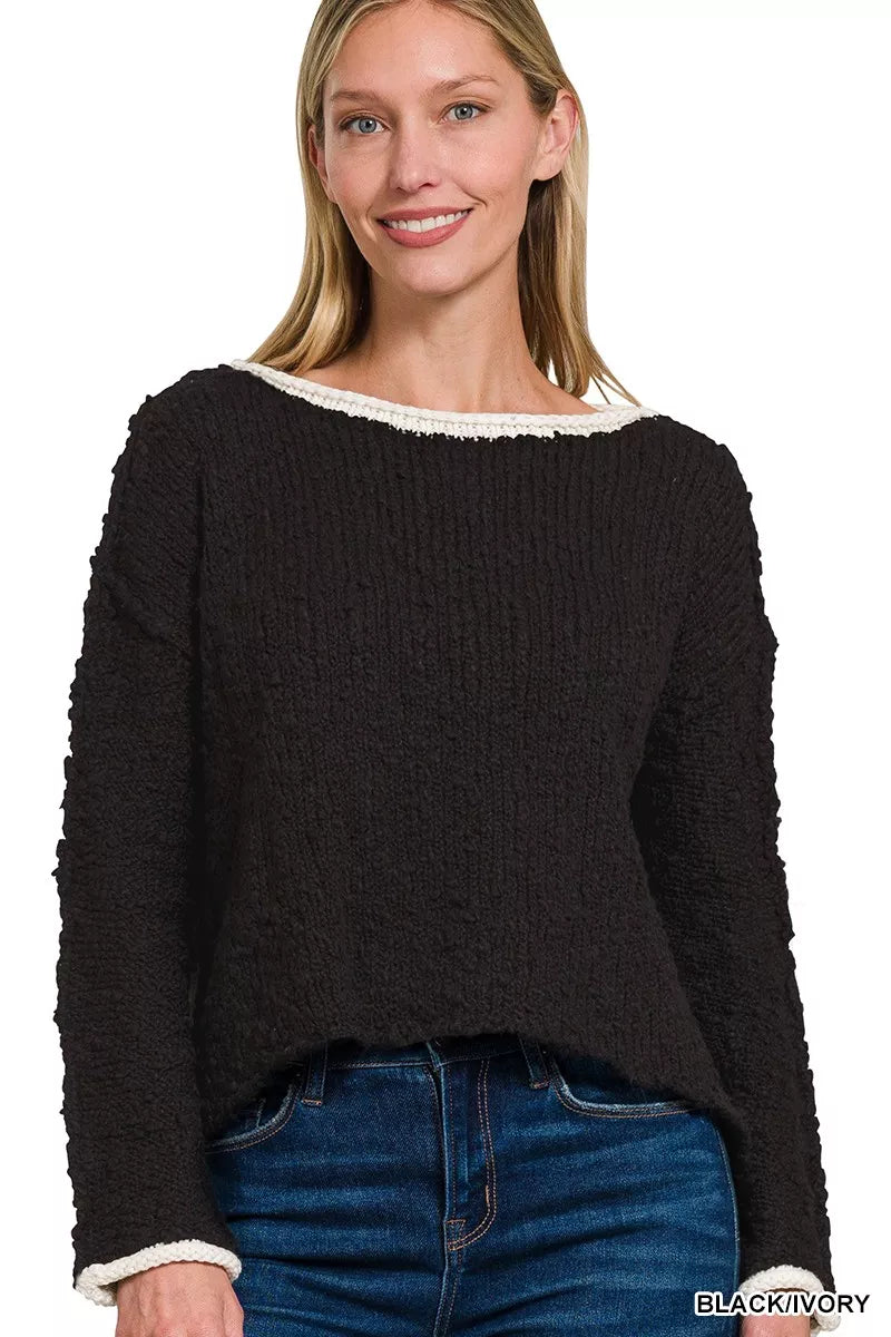 Model wearing the Solar Eclipse Contrast Sweater — a black textured cropped knit with ivory trim on the neckline and cuffs, styled with denim jeans.