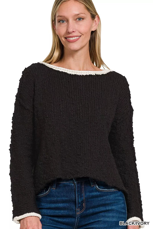 Model wearing the Solar Eclipse Contrast Sweater — a black textured cropped knit with ivory trim on the neckline and cuffs, styled with denim jeans.