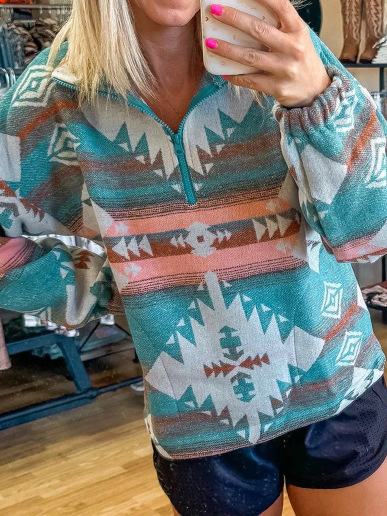 Turquoise Aztec print quarter zip sweatshirt with elastic cuffs.