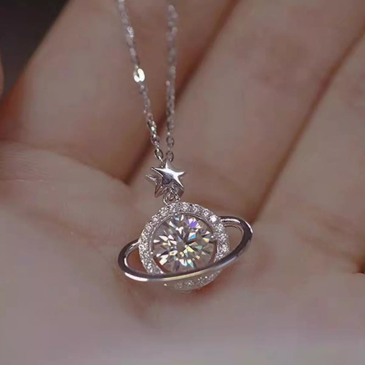Sterling silver Saturn-inspired pendant necklace with 1ct moissanite center stone, star accent, and matching jewelry box.