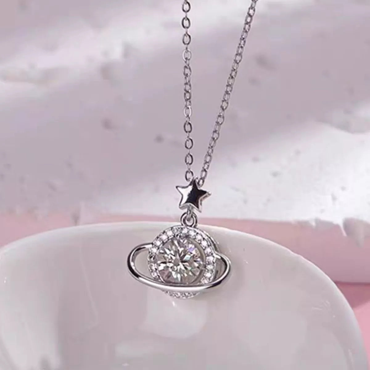 Sterling silver Saturn-inspired pendant necklace with 1ct moissanite center stone, star accent, and matching jewelry box.